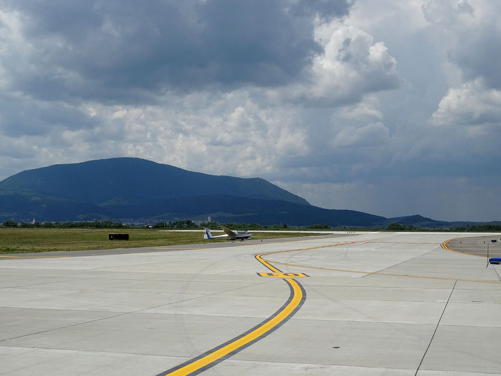 Platforma Aeroportului Brașov-Ghimbav, cu o aeronavă ușoară și Măgura Codlei în fundal