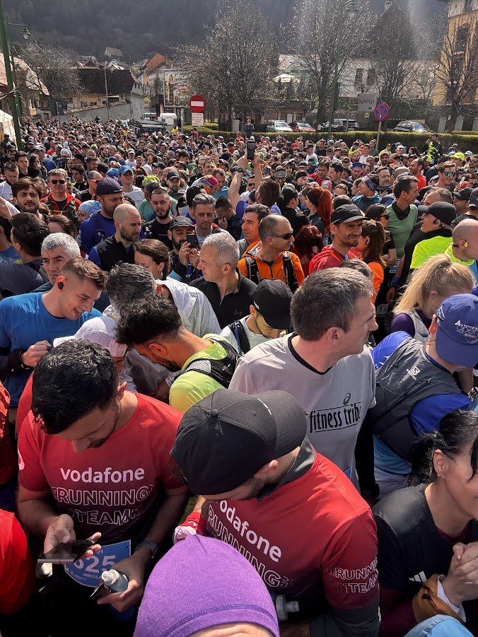 Alergători îngrămădiți la startul Semimaratonului Brașov, cu dealul împădurit în fundal